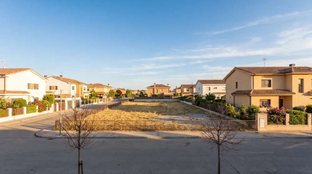 Solar urbano vacío entre viviendas unifamiliares